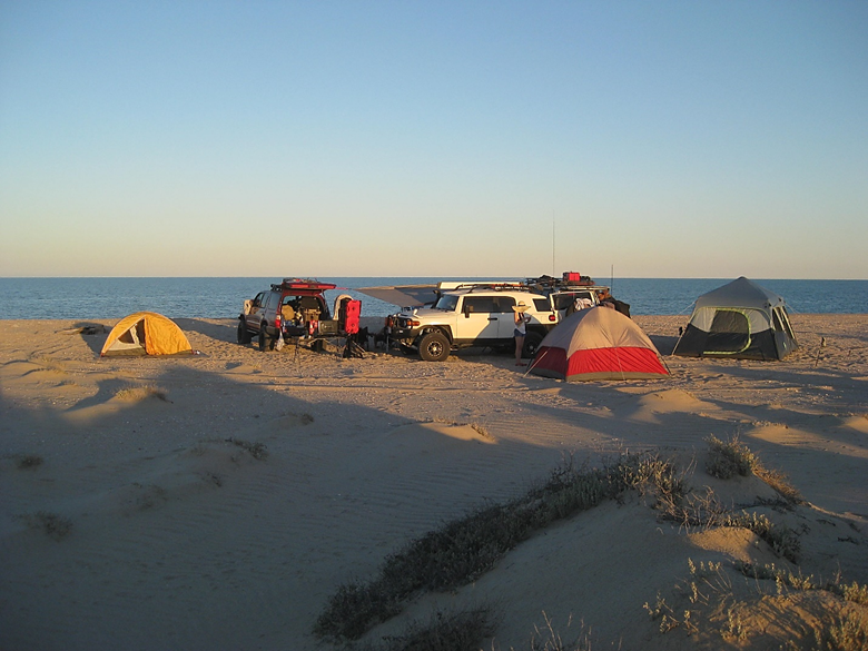 A group of people on a sandy beach next to the ocean