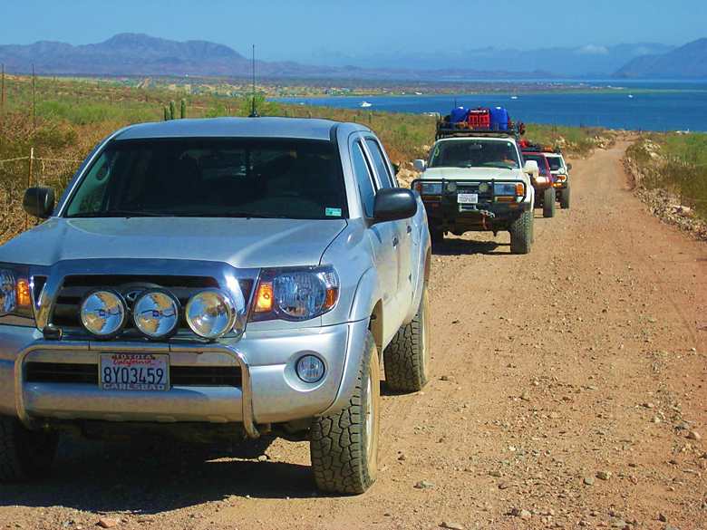 A car driving down a dirt road Description automatically generated