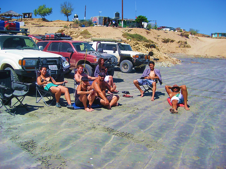 A group of people sitting at a beach Description automatically generated