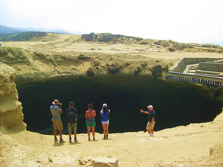A group of people standing on a rocky beach Description automatically generated