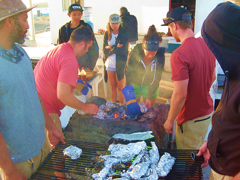 A group of people standing on top of a cutting board with a cake Description automatically generated